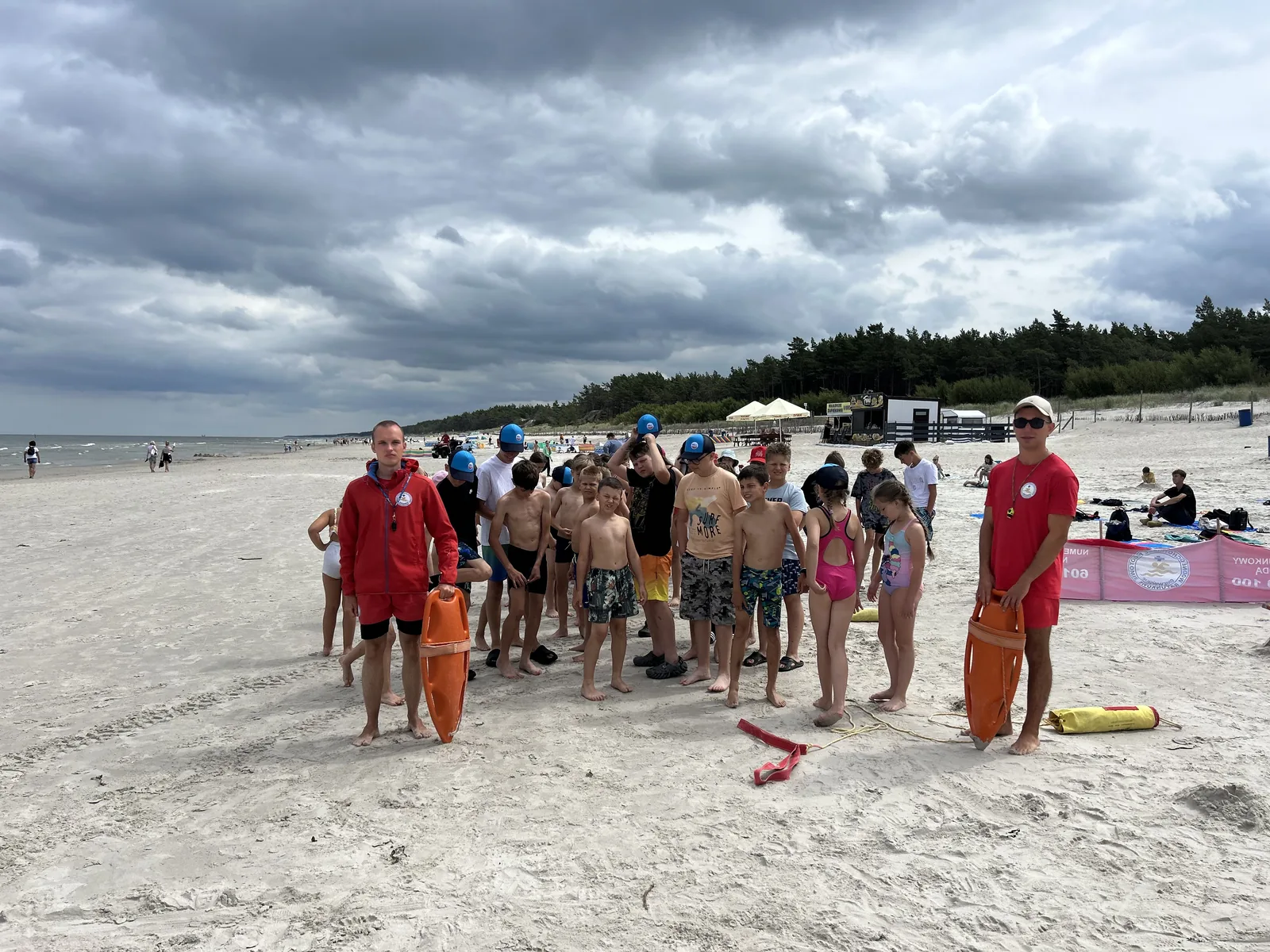 Grupa dzieci na plaży obok ratownika